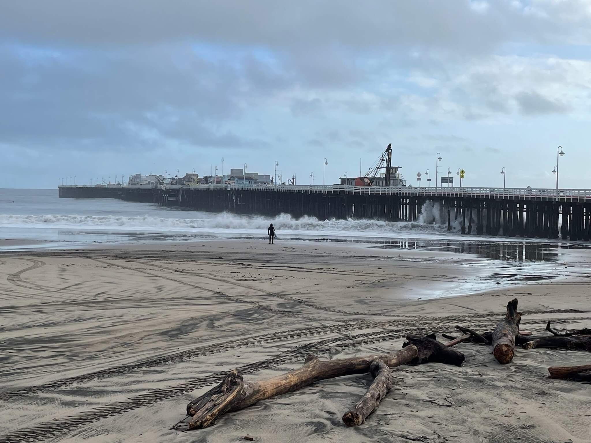 shot of santa cruz wharf with surfer standing in front