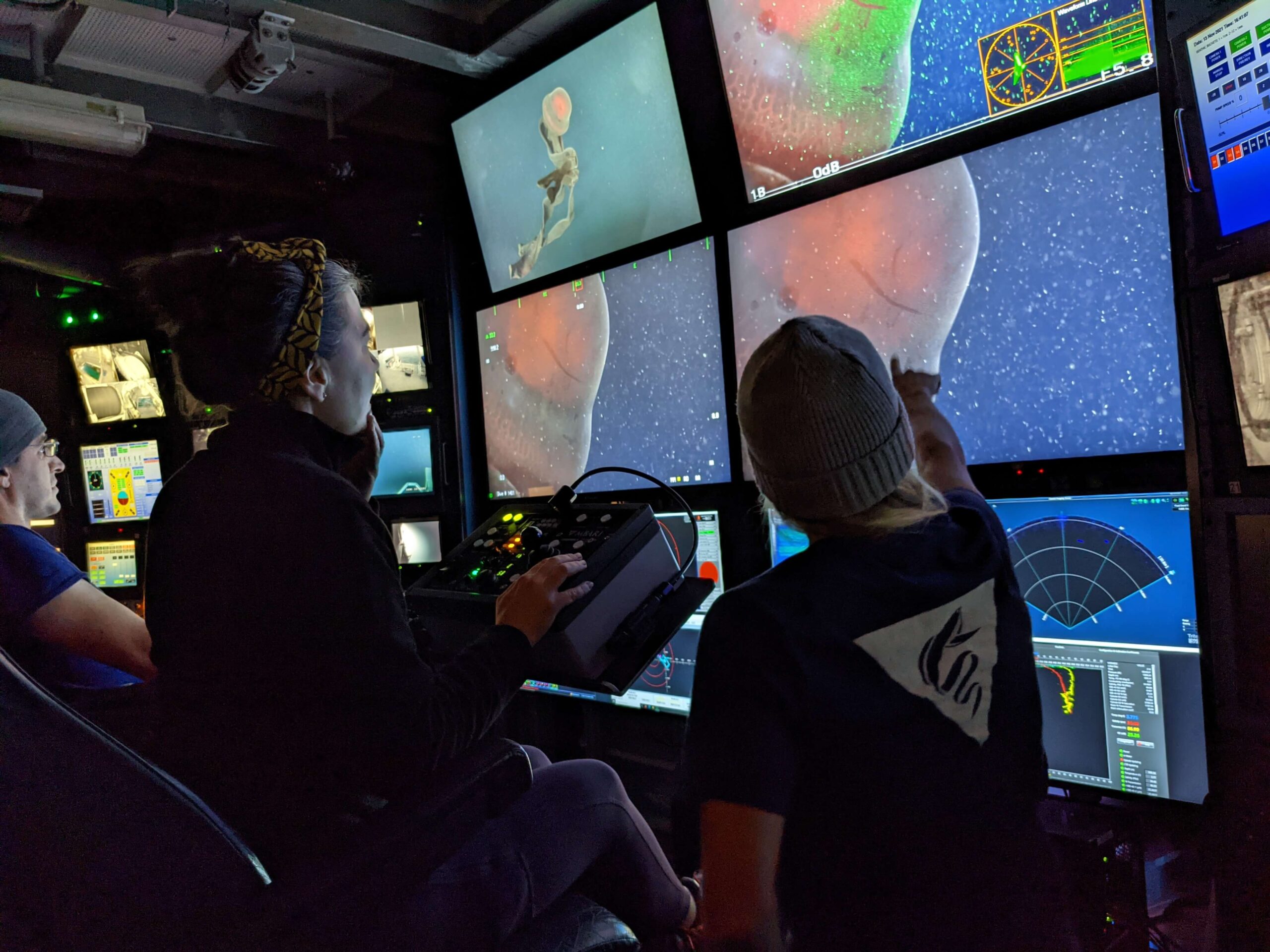 People viewing screens that show a red jelly captured from ROV footage on the Western Flyer