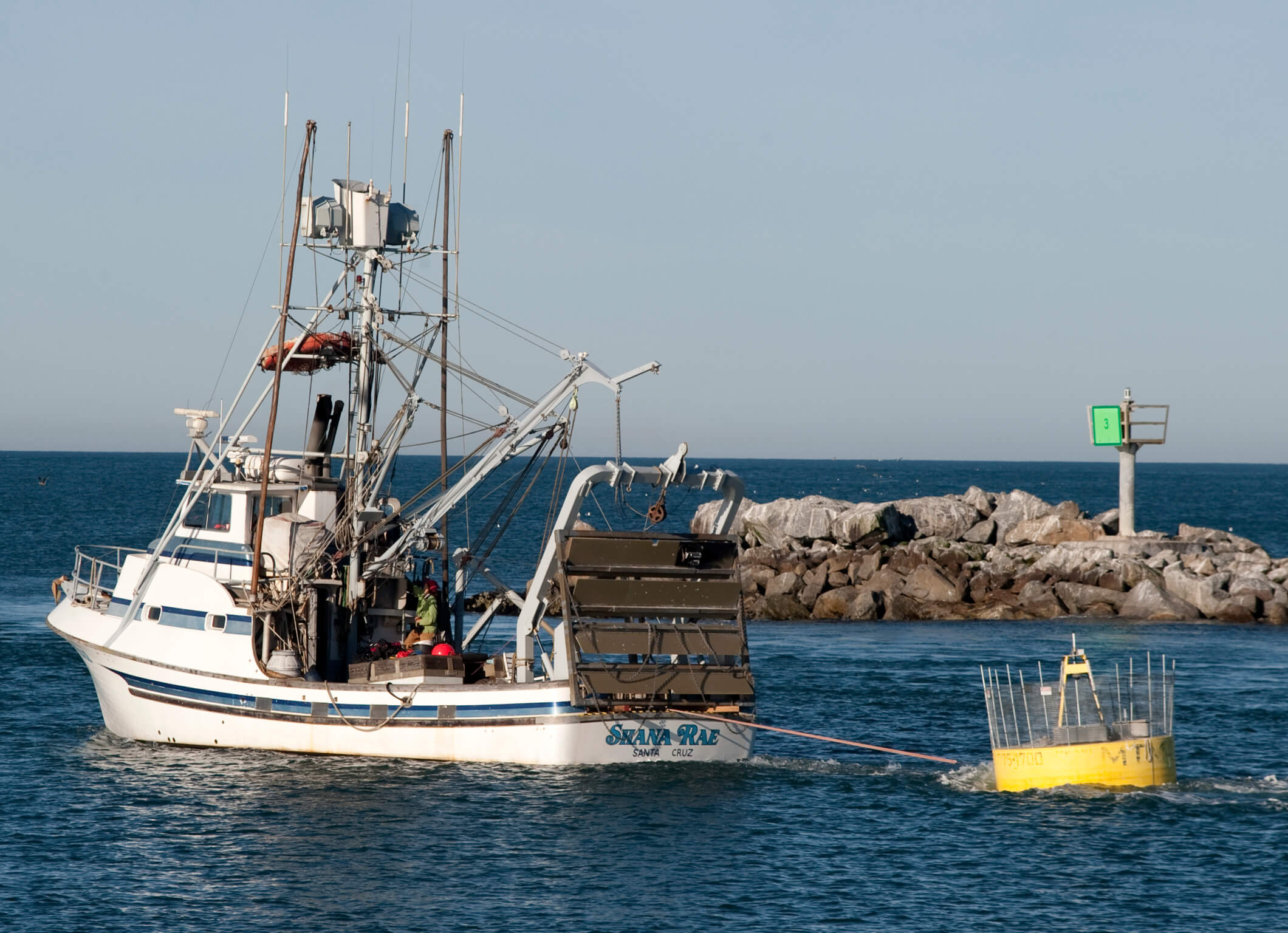 Wave-power buoy leaves the harbor in tow behind the Shana Rae